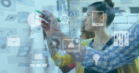 Brainstorming team members discussing ideas at office meeting area, glass board and digital icons