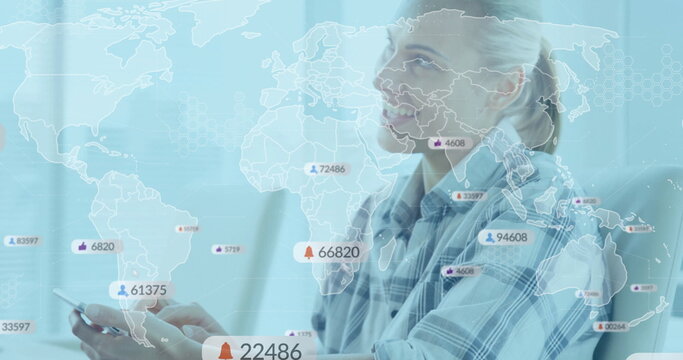 Woman in checkered shirt holding smartphone, gazing up at desk with world map overlay notifications - Powered by Adobe