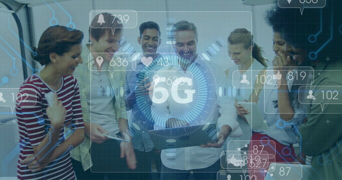 Gathering coworkers around laptop discussing in office area, with 5G icons, phone and coffee mug