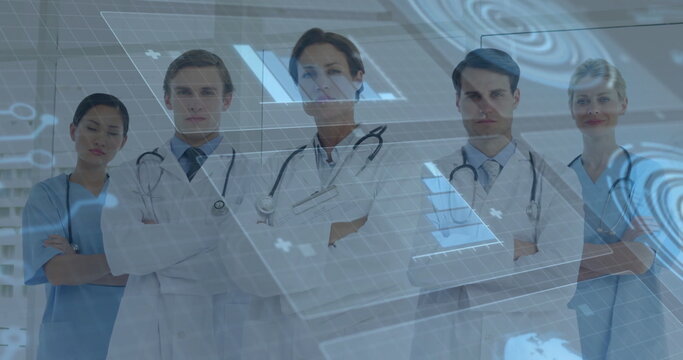 Standing medical team crossing arms in hospital corridor, displaying holographic interface panels - Powered by Adobe
