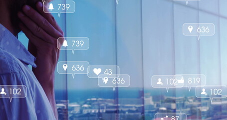 Standing man in blue shirt gazing at office window with ocean view, displaying alerts, copy space