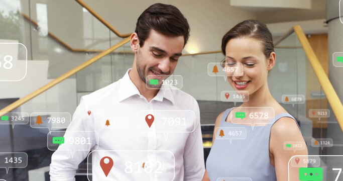 Reviewing digital overlays, colleagues in work attire standing in office lobby with floating icons