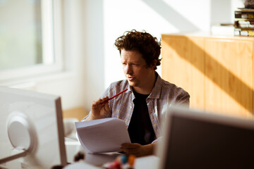 Man working at office desk with documents and computer monitor