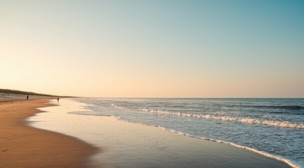 Obraz premium Scenic ocean waves gently washing onto the sandy shore at sunrise.