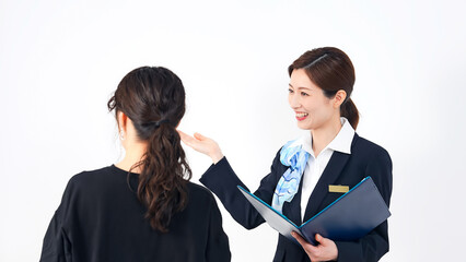 Smiling female store clerk, reception staff guiding customers in front of white background.