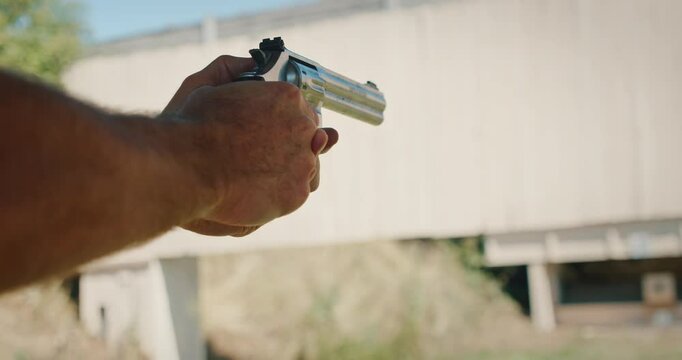 Person holding a revolver with both hands and firing at a shooting range