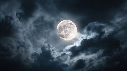 A stunning view of a full moon shining through thick, dark night clouds.