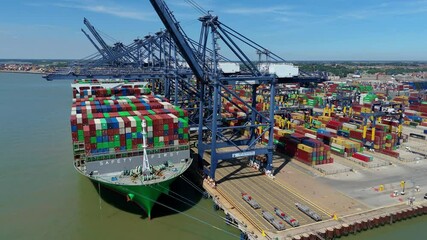 Aerial drone shot Felixstowe busy port cargo ships, shipping containers, huge cranes, loading and unloading heavy goods vehicles summer maritime business England UK. - Powered by Adobe