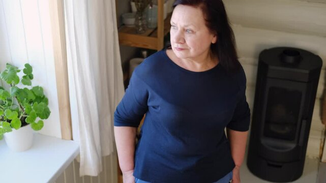 Senior woman dance at home. Elderly lady listening song and moving. Old female brunette feels calmly, relish carefree retired life looks happy. Vitality, wellness. Grandmother dancing alone indoors.