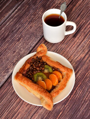 Sweet puff pastry pie with kiwi and tangerine slices, sprinkled with coffee beans and a cup of hot...