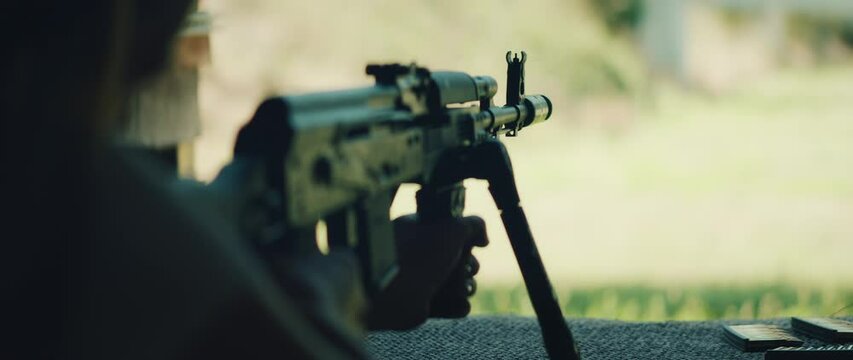 Person aiming with rifle on bipod at outdoor shooting range