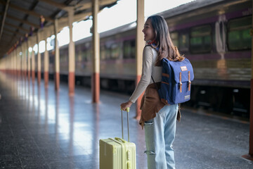 A woman is walking with a suitcase and a backpack