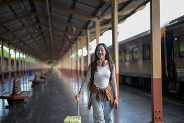 A woman is walking through a train station with a suitcase