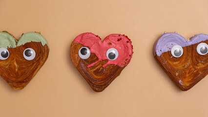 Funny personalized eyes Creative ides Valentine's Day flat lay top view Holiday celebration Heart shaped different variety flavor croissants on beige background with copy space. Puff pastry new trendy