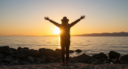 Person with outstretched arms on beach at sunset