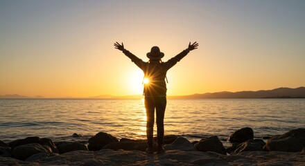 Person with outstretched arms on beach at sunset