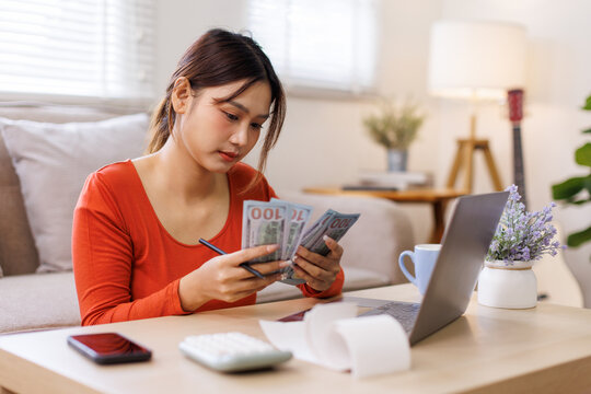 Money cash dollar rain falling, Financial concept. Make money on the Internet. Asian woman sitting on the desk and working with a laptop celebrating success play casino online game.
