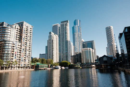 Modern skyscrapers reflecting on millwall inner dock water in canary wharf, london, during a sunny day