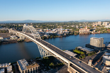 Obraz premium Aerial drone picture of Portland’s Fremont Bridge at sunset, the Willamette River, Downtown Portland, industrial area, and Mt. Hood in the background, with clear blue summer sky