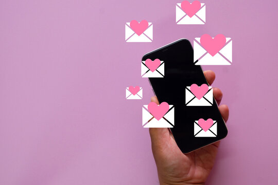 Online dating app concept. Hand holding a smartphone receiving many love messages or match notifications. Finding romance and love online through modern technology. Chatting with a romantic partner.