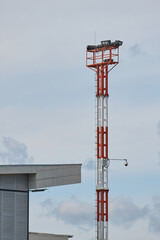 Airport Lighting Tower with Security Camera Under Cloudy Sky
