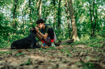 Dog trainer petting doberman pinscher in forest during training session