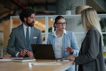 Business team discussing strategy in modern office using laptop