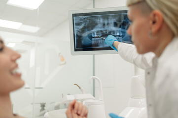 Dentist showing teeth x ray to patient in modern clinic