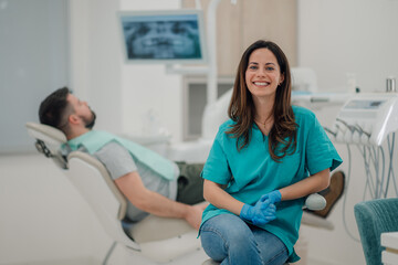 Dentist smiling at dental clinic with patient waiting for treatment