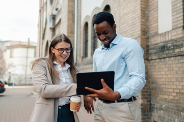 Business colleagues using digital tablet outdoors and smiling