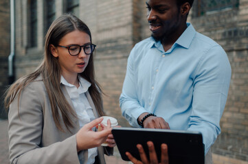 Businesspeople using tablet and drinking coffee outdoors