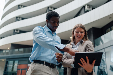 Business colleagues using tablet and discussing project outside office building