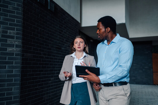Business colleagues walking and discussing a project using tablet