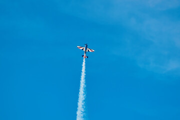 Aerobatic Airplane Performing Smoke Maneuver in Blue Sky