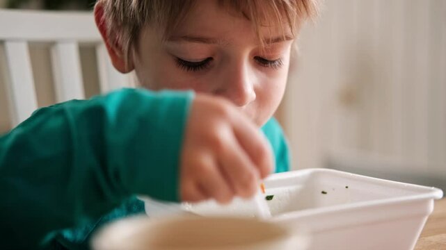 6 years old boy eats instant noodle from box. Child is eating spaghetti. Lunch time. A good appetite. Tasty children food. Close-up portrait. Carbs dinner. Fast food. Kid eating by himself with fork.