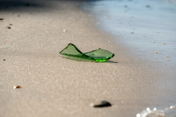 Green Glass Shard on Sandy Beach Shoreline at Sunrise