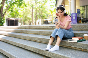 Smiling student   listening to favorite radio station  holding smart phone on steps in campus.