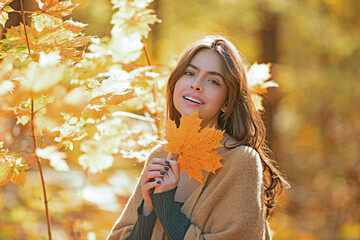Autumn face of happy young woman. Smiling woman on autumn fall background. Beauty girl with fall...