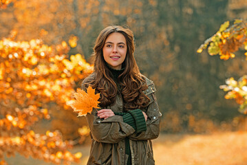 Autumn woman with fall yellow maple leaf near face, outdoor portrait. Girl with autumn leaves....