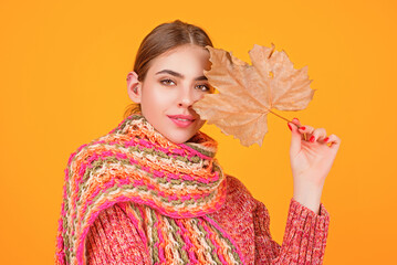 Portrait of woman with autumn leaf on face. Woman portrait close up on autumn background. Woman...