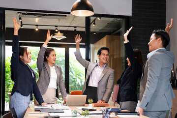 Team of happy diverse company employees raising hands for good agreement in corporate meeting....