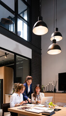 Confident mature business professional woman talking to younger female colleague at office table,...