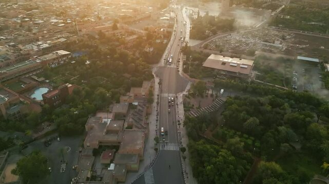 Drone sunrise aerial view over the city of Marrakech with the historic Medina, the bustling souk, and the majestic Atlas Mountains rising in the background, bathed in golden morning light
