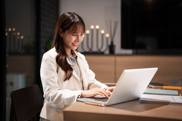 Young asian businesswoman using laptop for remote work .young woman sits at office desk , texting,...