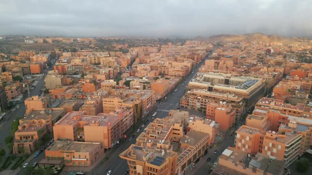 Aerial panoramic view of Marrakech city at sunrise with soft morning light illuminating terracotta buildings and streets in Morocco