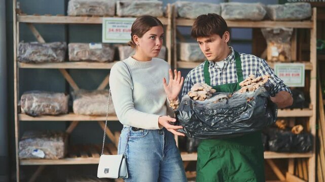 At garden center, guy seller talks about mycelium to girl buyer, explains principles of growing oyster mushrooms from seeds on special soil. Employee gives advice and talks about gardening life hacks