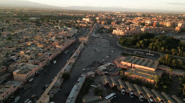 Aerial panoramic view of Marrakech city at sunrise with soft morning light illuminating terracotta buildings and streets in Morocco