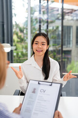 Female Asian applicant with human resources manager at job interview in office.