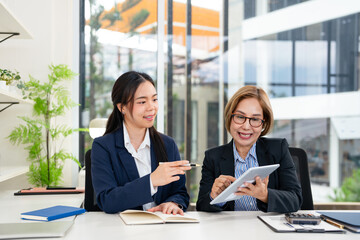 Two business women sit at desk discuss project details, diverse female colleagues met in office,...