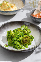 Steamed broccoli garnish, bright natural lighting, shallow depth in modern overhead plate